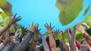 Menschen, die gemeinsam einen großen Globus hochheben, symbolisieren Einheit und globale Zusammenarbeit.